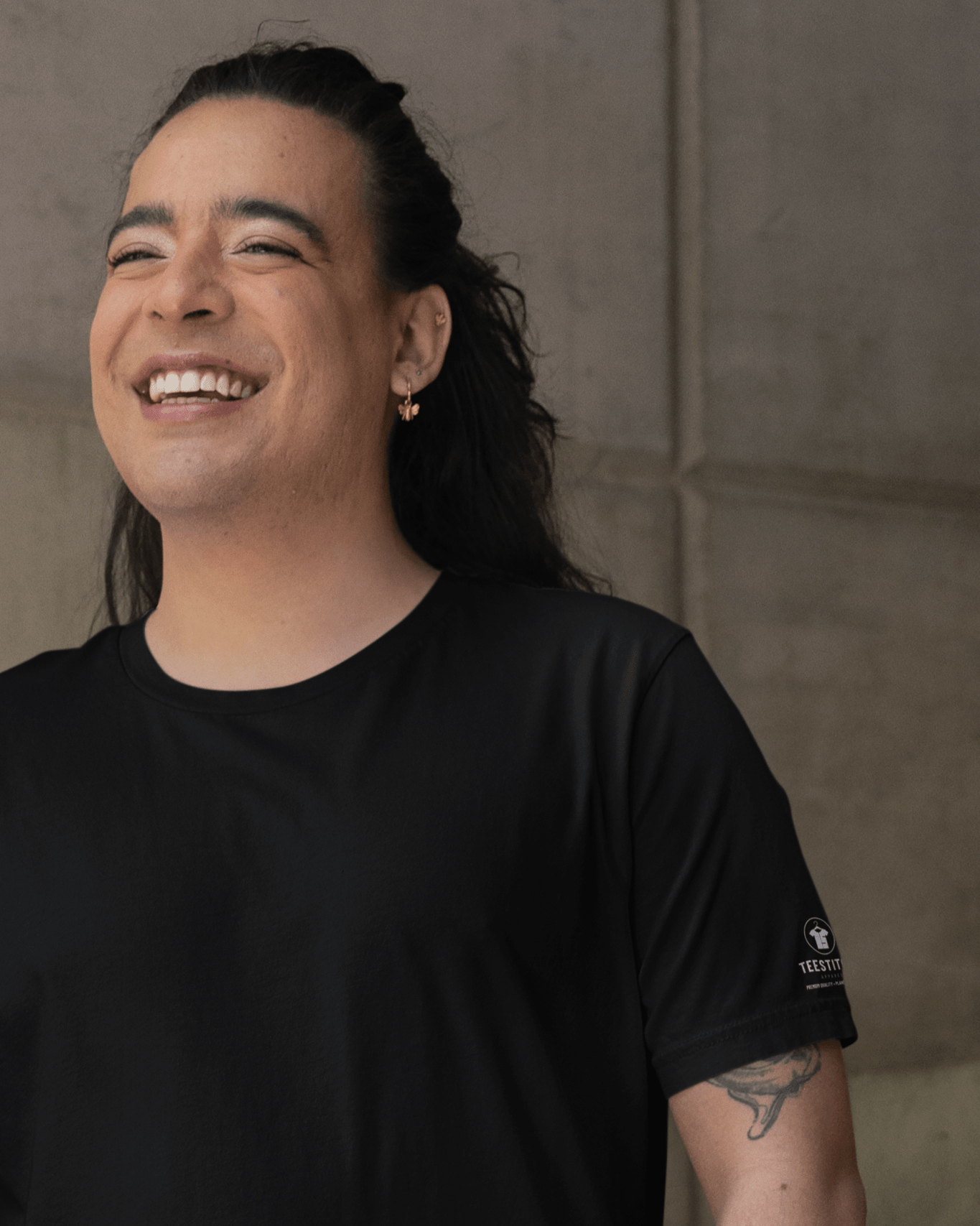 TeeStitch-Core-Essentials-t-shirt-mockup-featuring-a-tattooed-person-with-a-joyful-smile