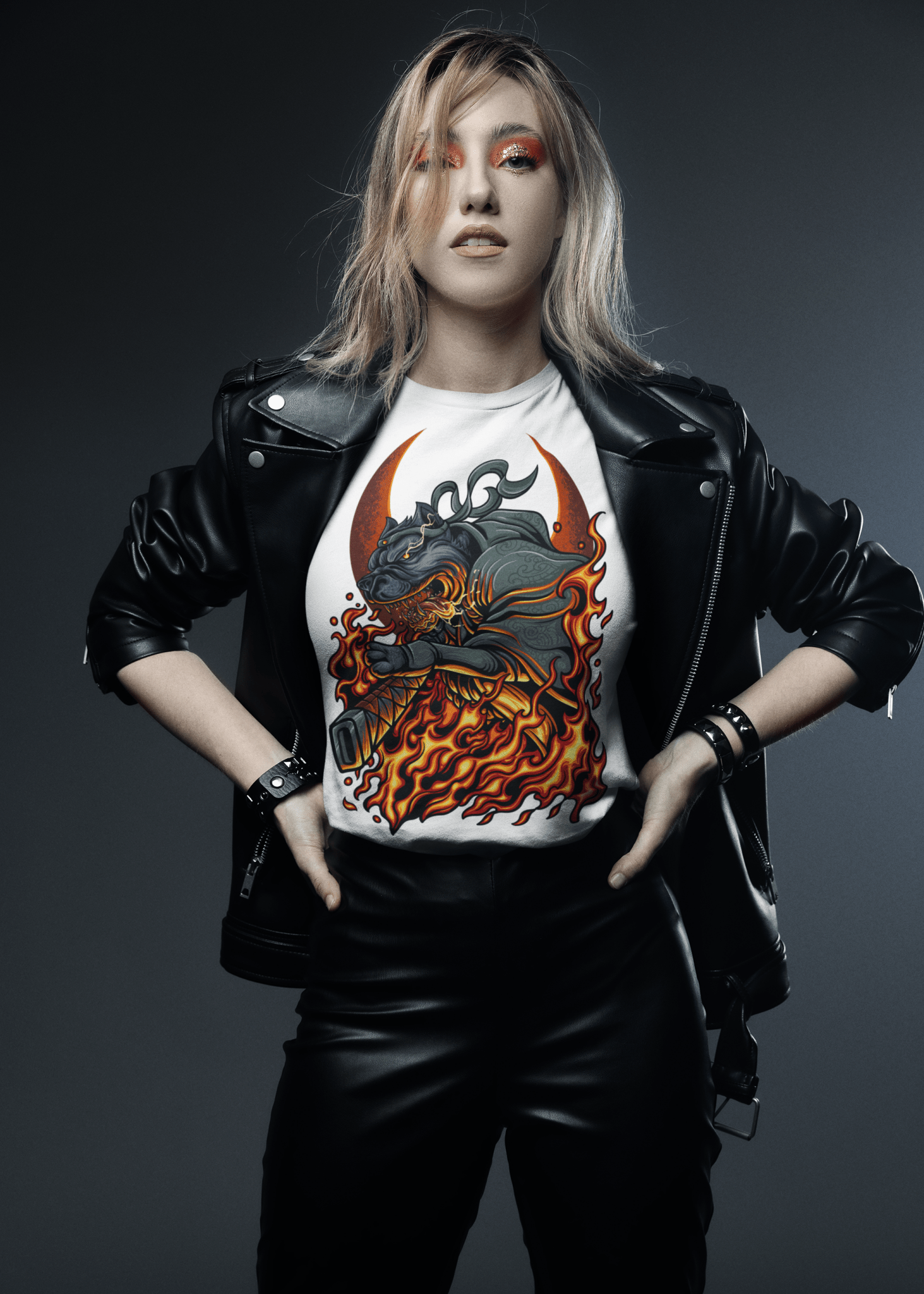 Person wearing a black leather jacket and pants with a graphic t-shirt on a dark background