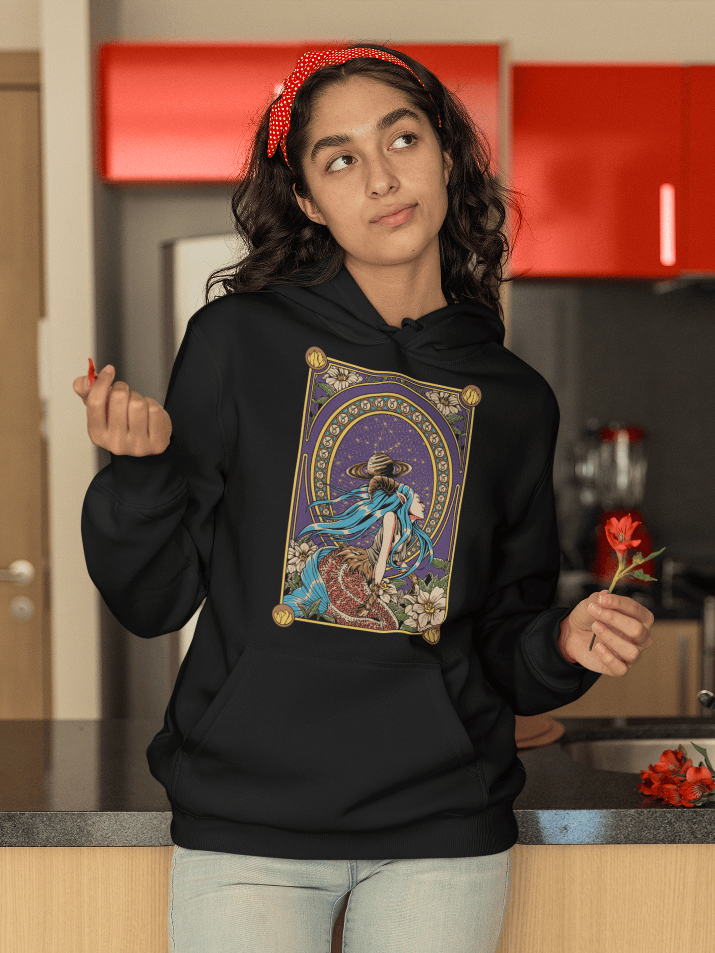 Person wearing a black hoodie with a colorful graphic design in a kitchen.