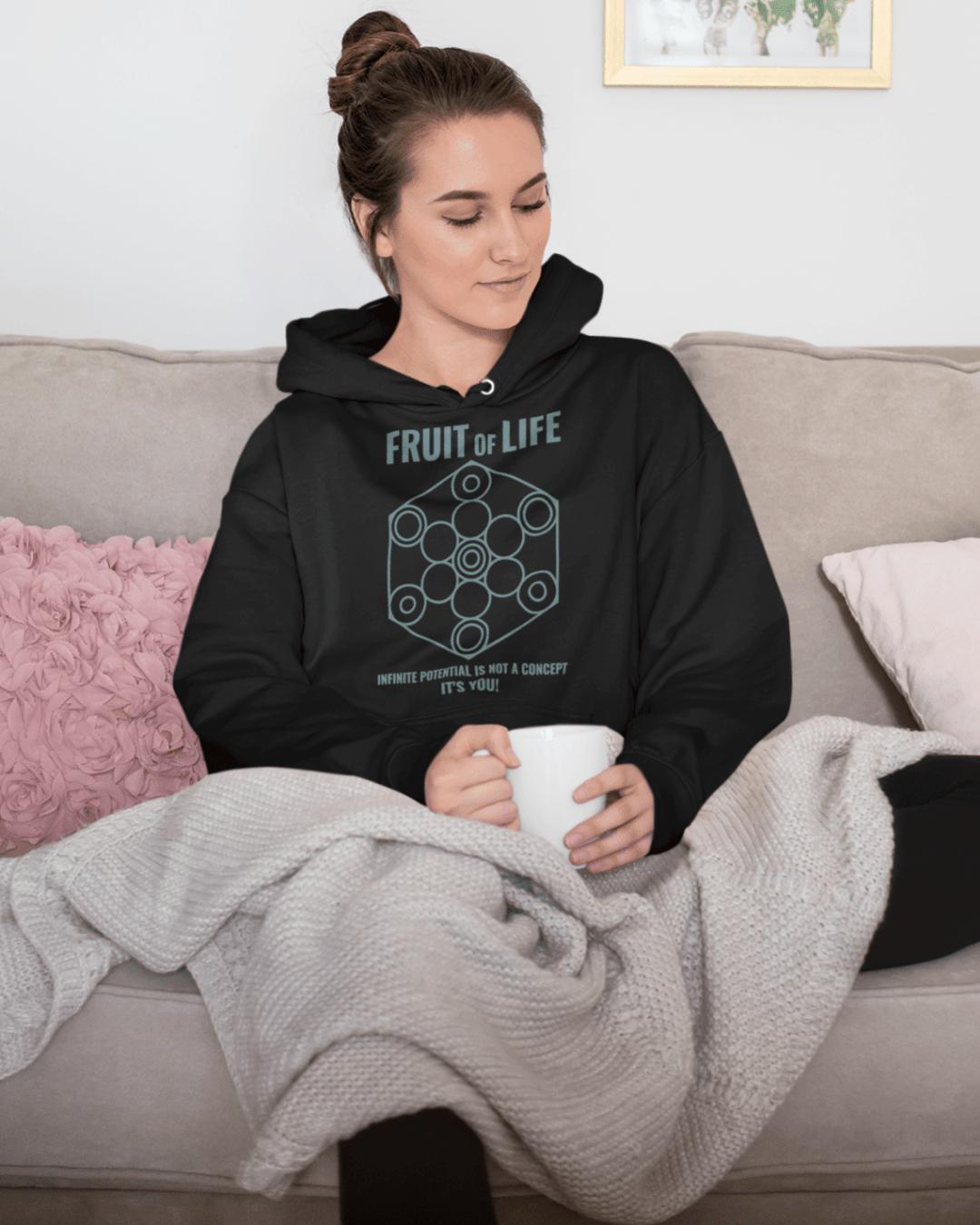 fruit-of-life-hoodie-mockup-featuring-a-beautiful-woman-on-her-sofa