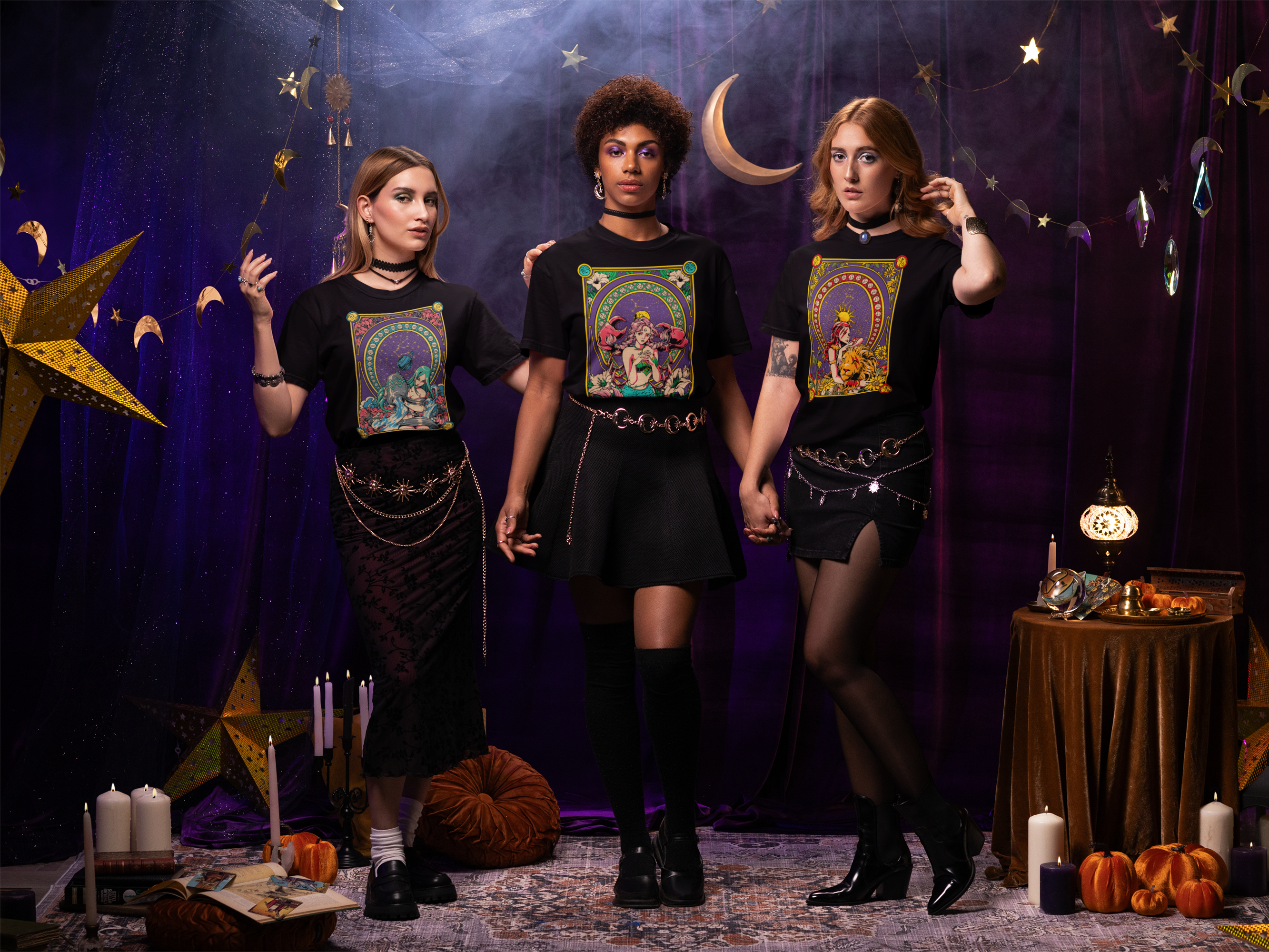 Three women wearing black t-shirts with colorful designs in a mystical setting.