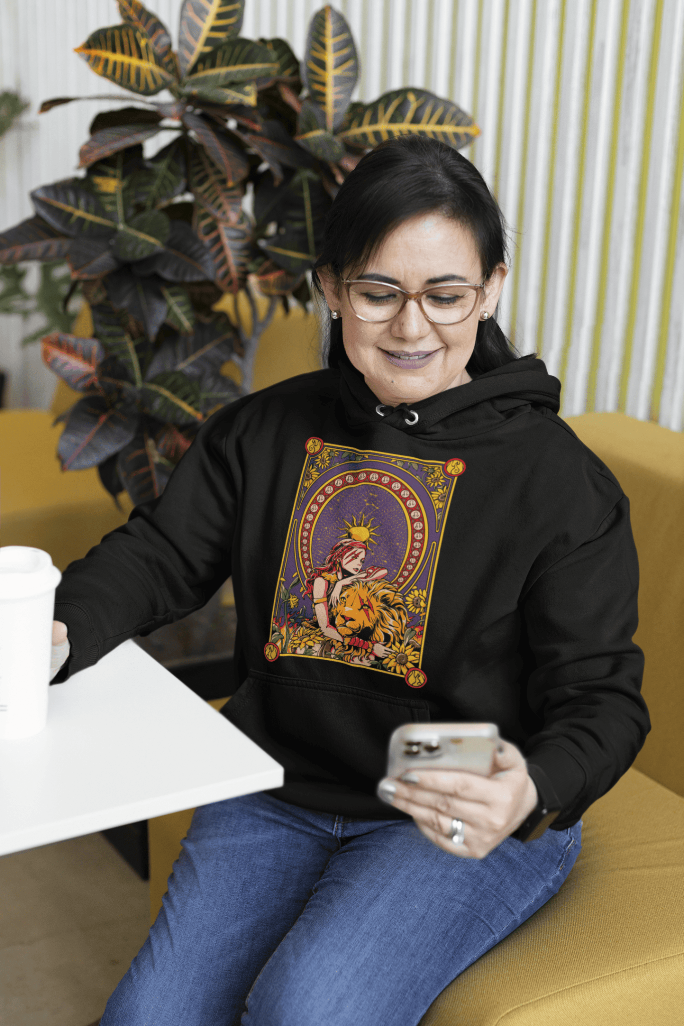 Person wearing a black hoodie with a colorful graphic design, sitting on a yellow couch.